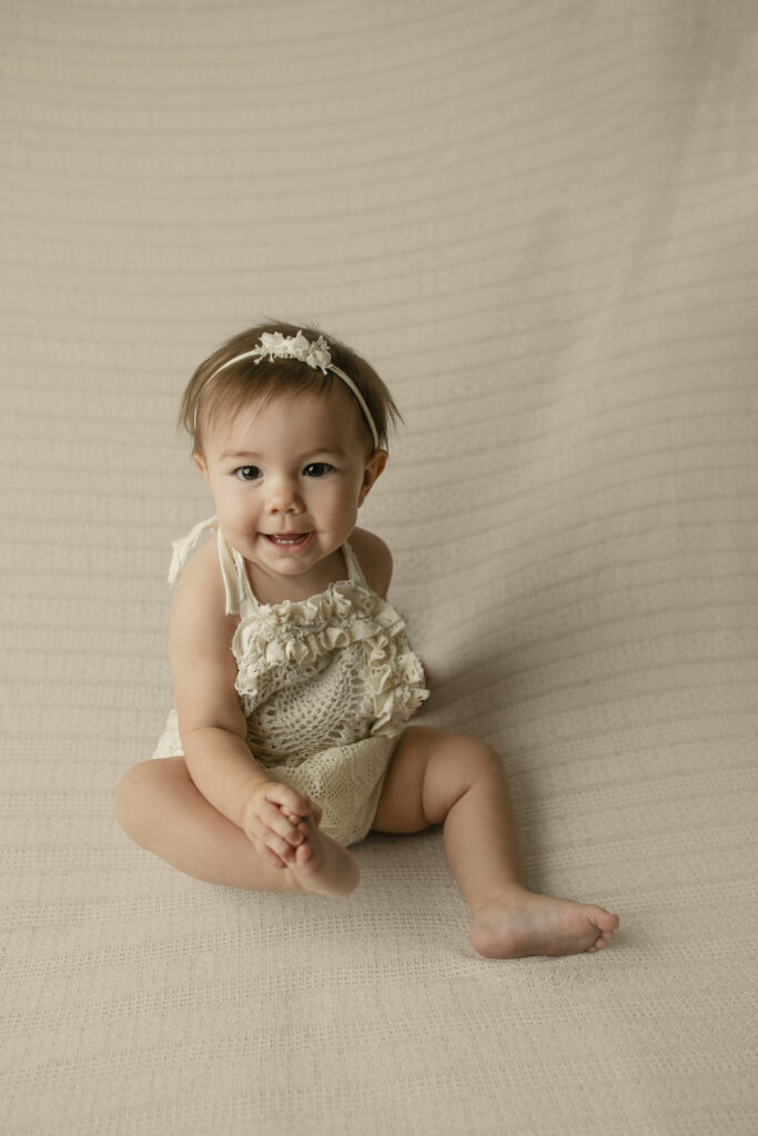 little girl in a romper holding her toes